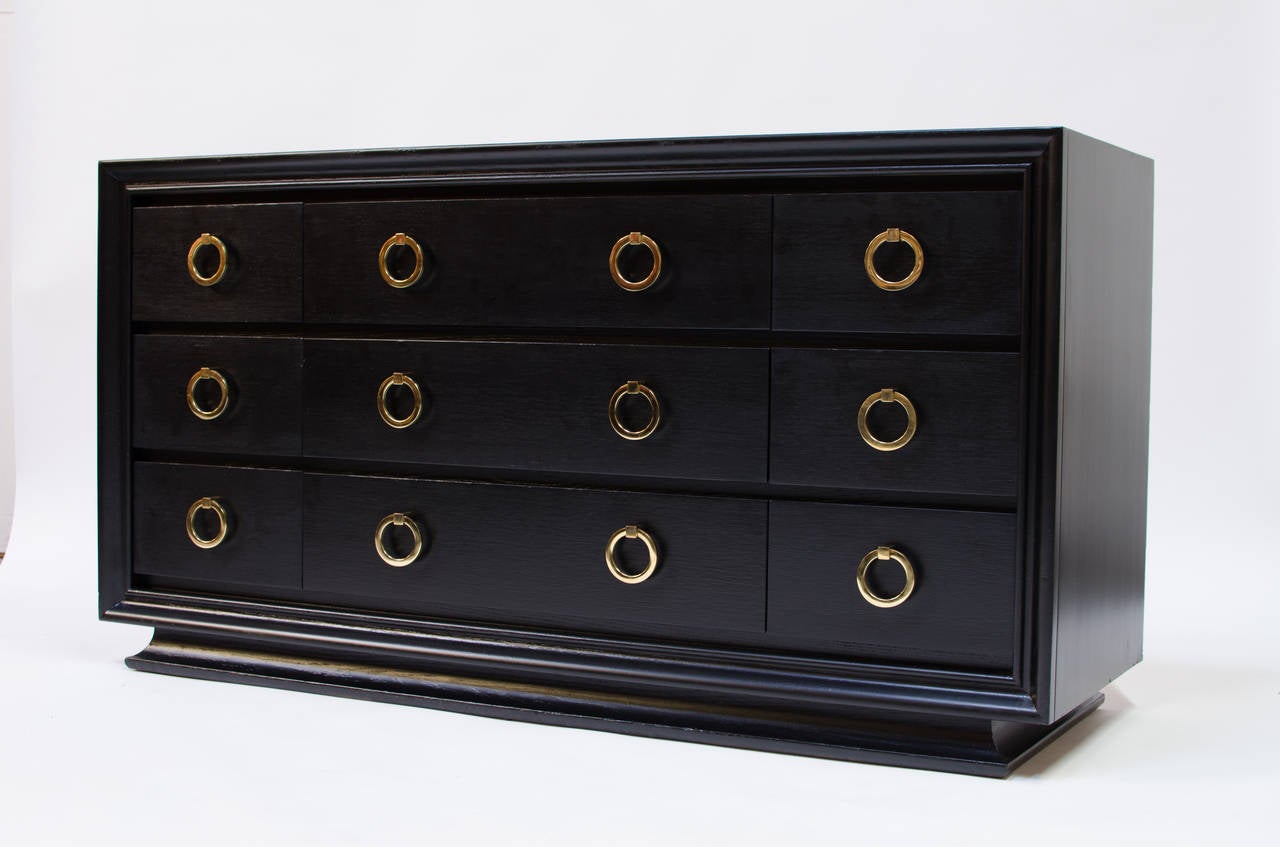 A fine example of an American Mid-Century dresser similar to designs by T. H. Robsjohn-Gibbings for Widdicomb, circa 1940. Featuring solid brass ring pulls which compliment the black lacquer finish perfectly. Restored condition.