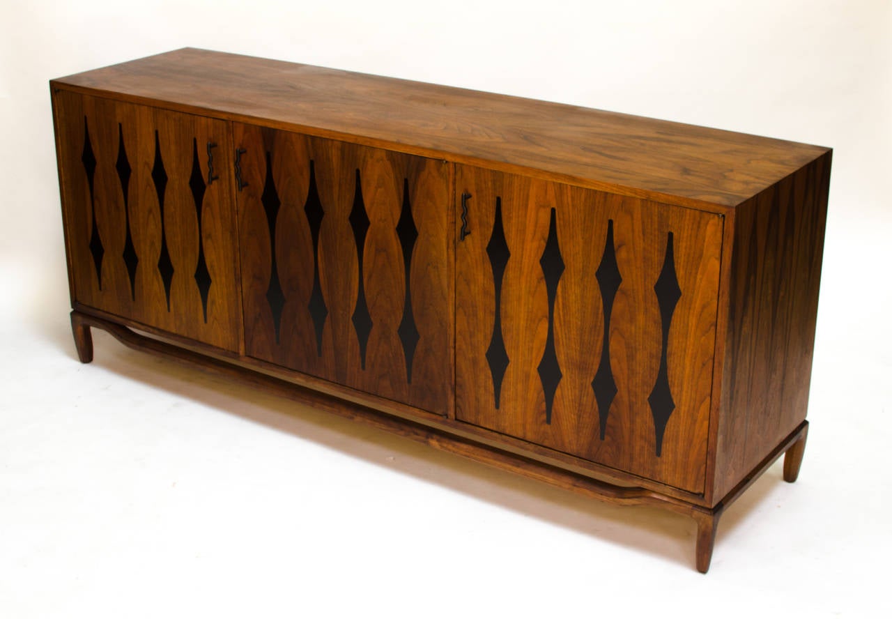 A fantastic walnut sideboard made by the Cal-Mode Company of Visalia California circa 1950s. A well made piece, it features wonderful grain and inlaid formica on the door fronts. Offered in restored condition w/manufacturers label.