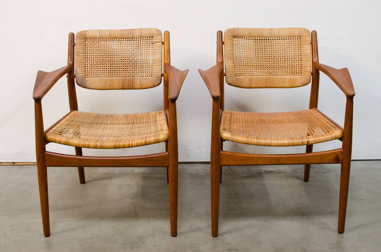 A rarely seen pair of armchairs designed by Arne Vodder for Sibast. This set features the original cane seats and backs, is completely original in unrestored condition, and the design of the upward sweeping arm is fantastic. The armrests gently