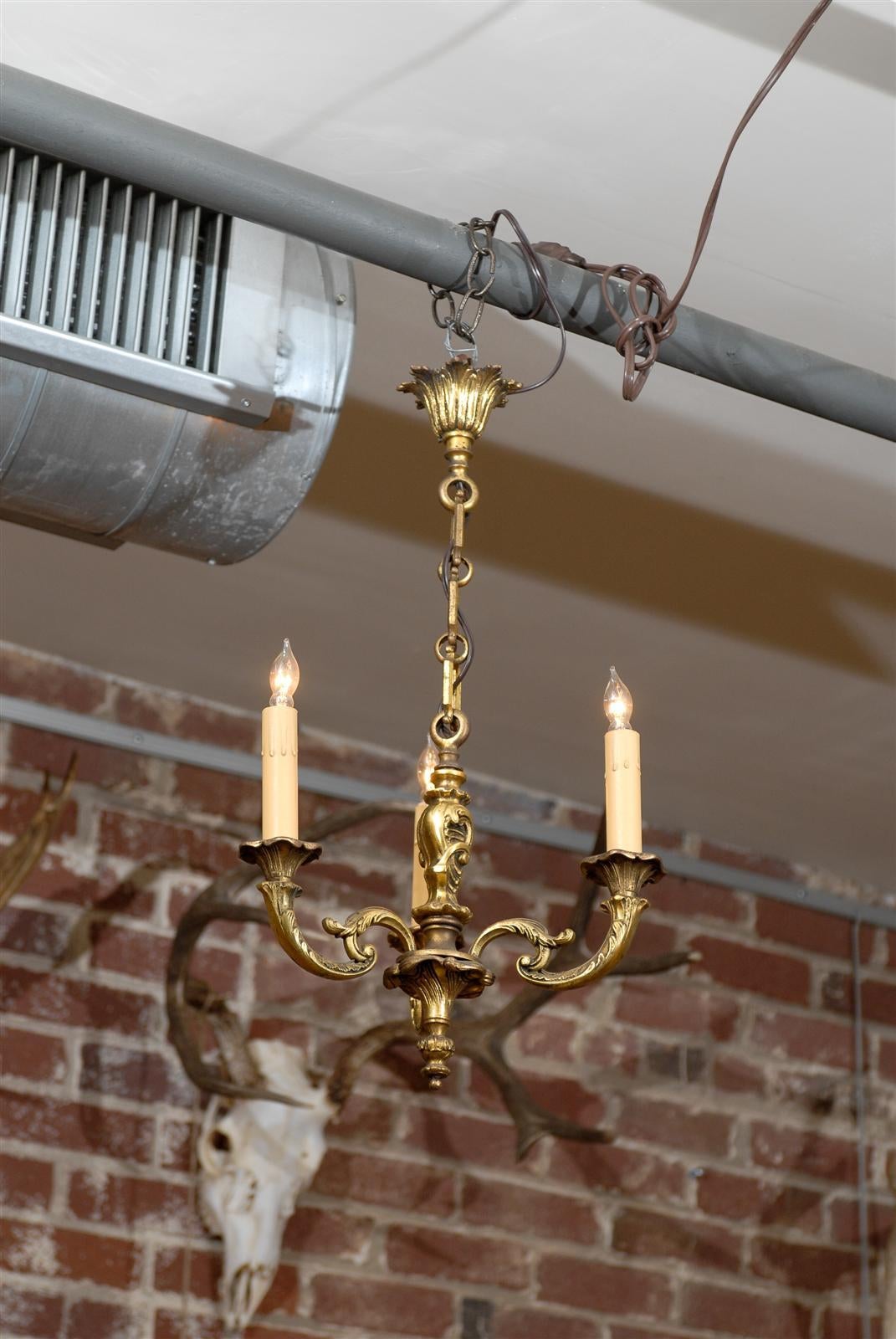 Early 20th Century French three arm chandelier of bronze supporting candlesticks.