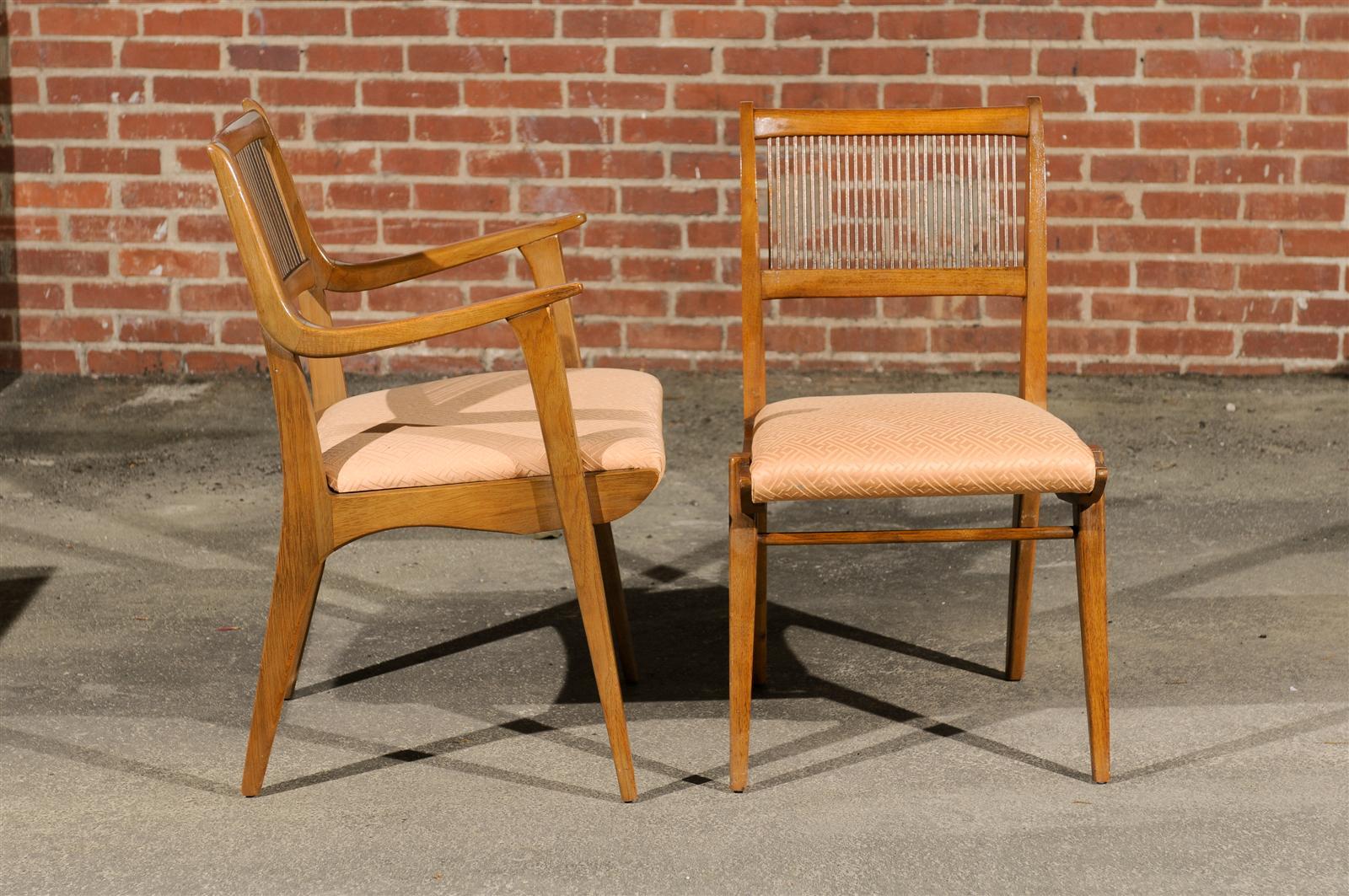 The Mid-Century Modern dining suite of ashwood is in the original condition and designed by John O. Van Koert for Drexel's Profile Series. It includes the dining table, two armchairs, and four side chairs. The chair upholstery fabric is in fair