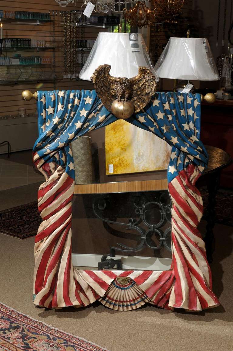 Rare and unusual Mid Century mirror having whimsical cascading stars and stripes molded of plexiglass and draping around the frame.  A giltwood eagle perched on a ball adorns the crown while a red, white, and blue fan completes the base.  Its origin