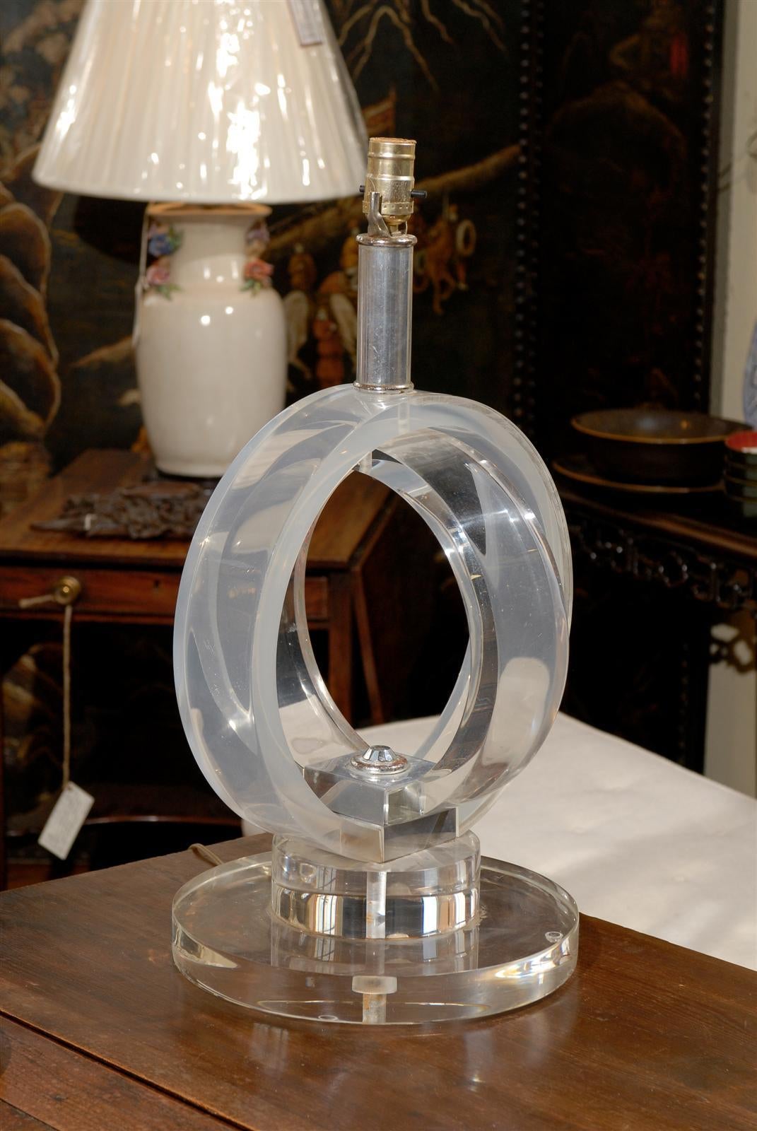 Midcentury table lamp of thick and heavy lucite concentric rings, one clear and the other frosted, on a substancial two tiered lucite base and having chrome fittings.
