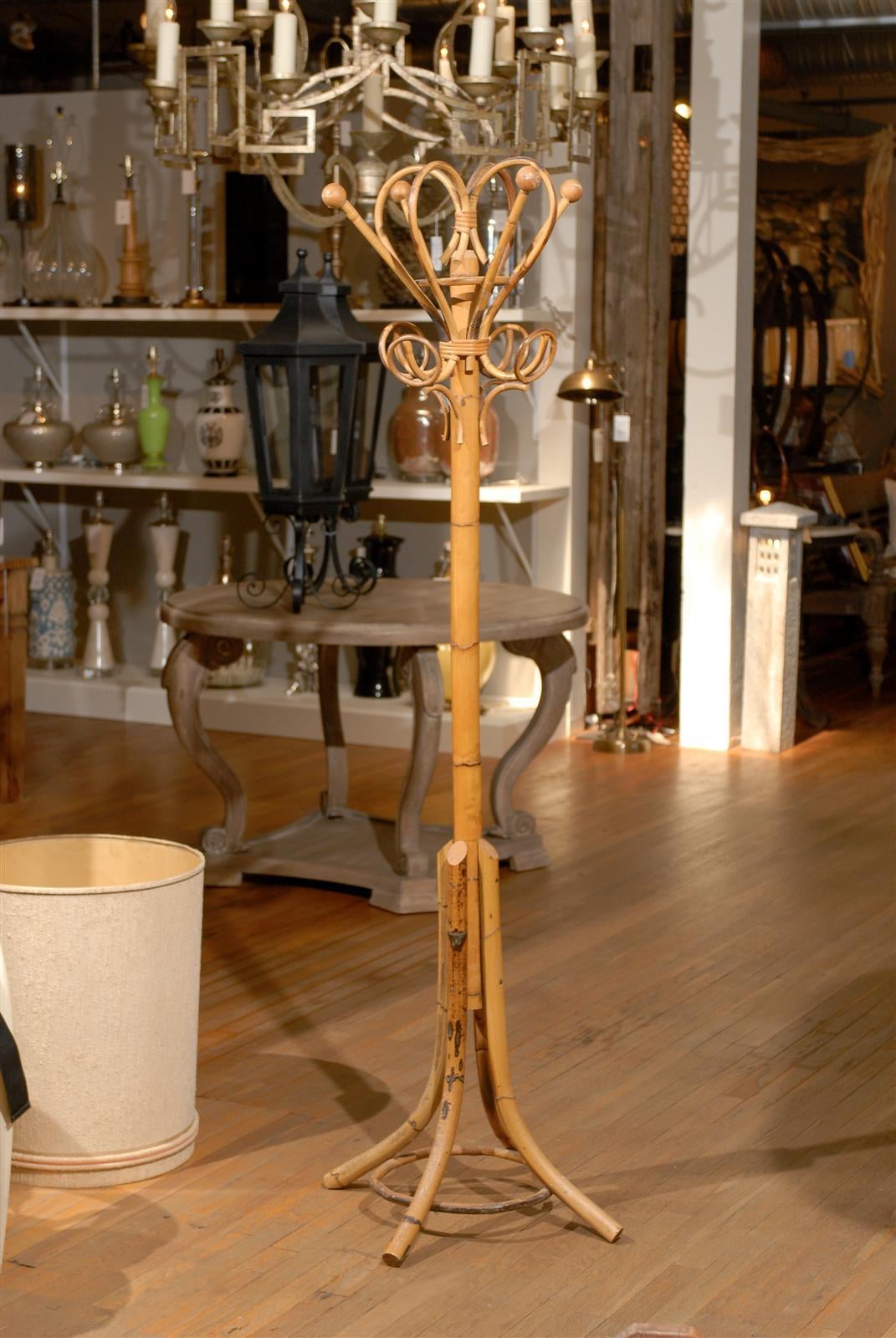 Vintage rattan hall tree or stand with a decorative bentwood hat and coat rack above a bamboo pedestal and resting on four outswept legs with a circular stretcher.