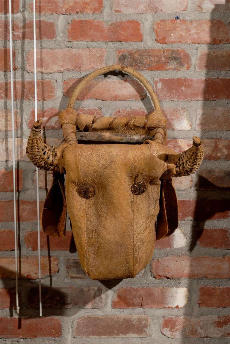 Charming primitive basket in the shape of a cow or bull head made of wicker, straw, leather, wood, and with button eyes.