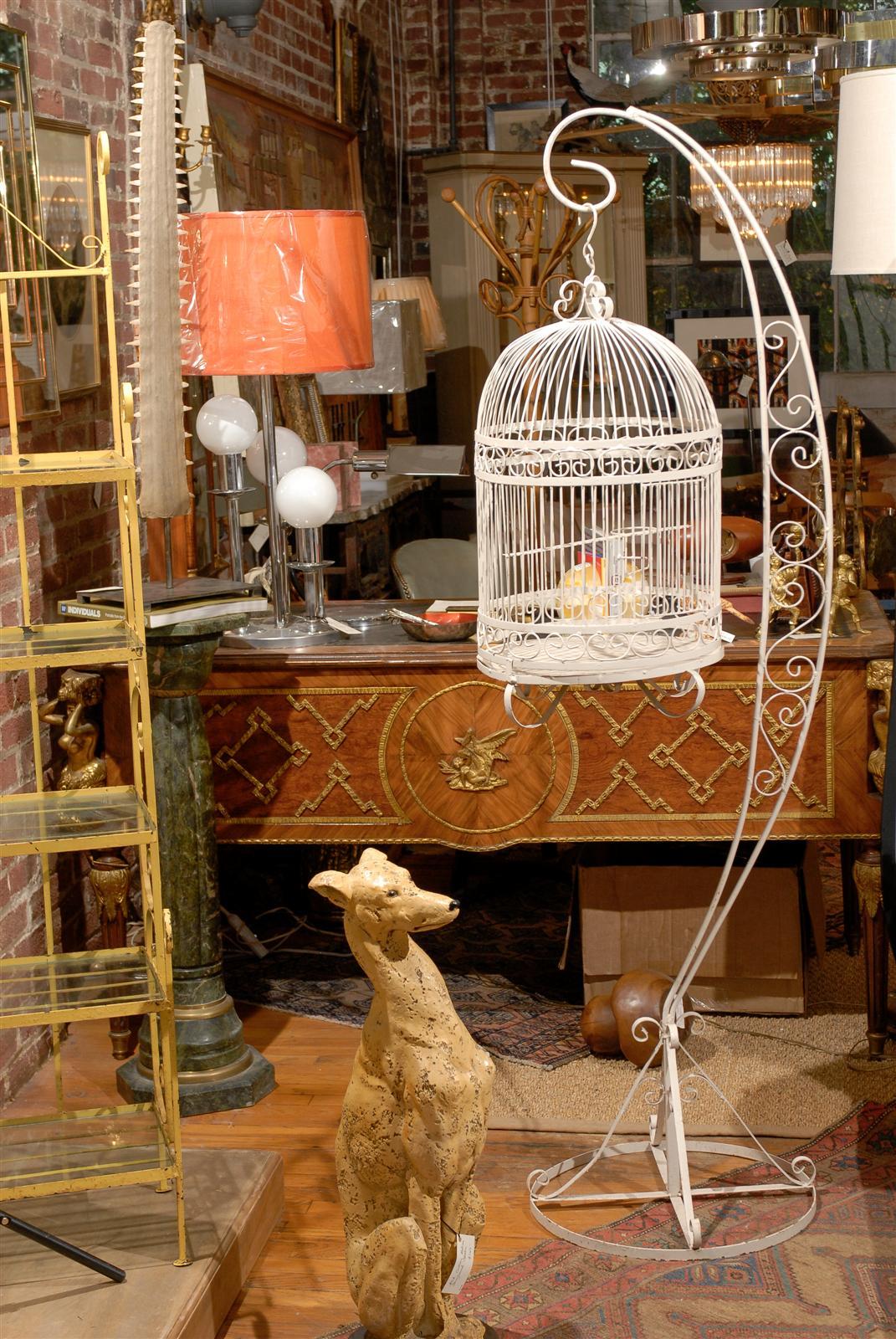 20th Century bird cage of scrolling iron work that suspends from a matching iron stand.  Both in the original white paint.