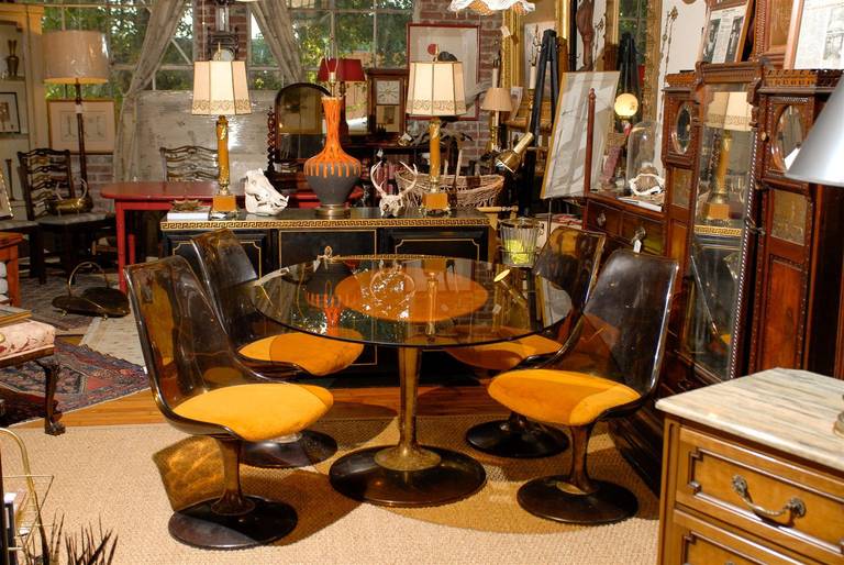 Mid-20th century American set of dining chairs and table all resting on bronzed columns and smoked Lucite tulip shaped bases. The chair backs are also of smoked Lucite and the upholstery is original. A camel colored vinyl platform holds the smoked
