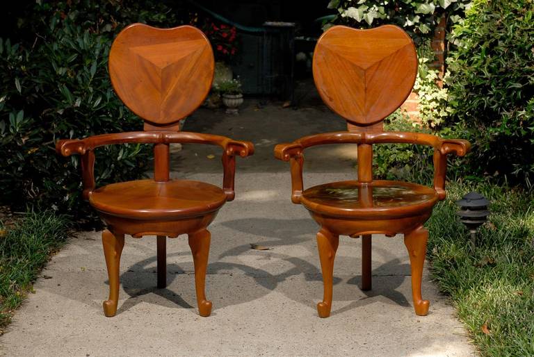 Pair of American Mid Century arm chairs of the finest craftsmanship created in the style of Antoni Gaudi.  A heart shaped back rests over outswept arms, a heavy round chair seat, and three cabriole legs.