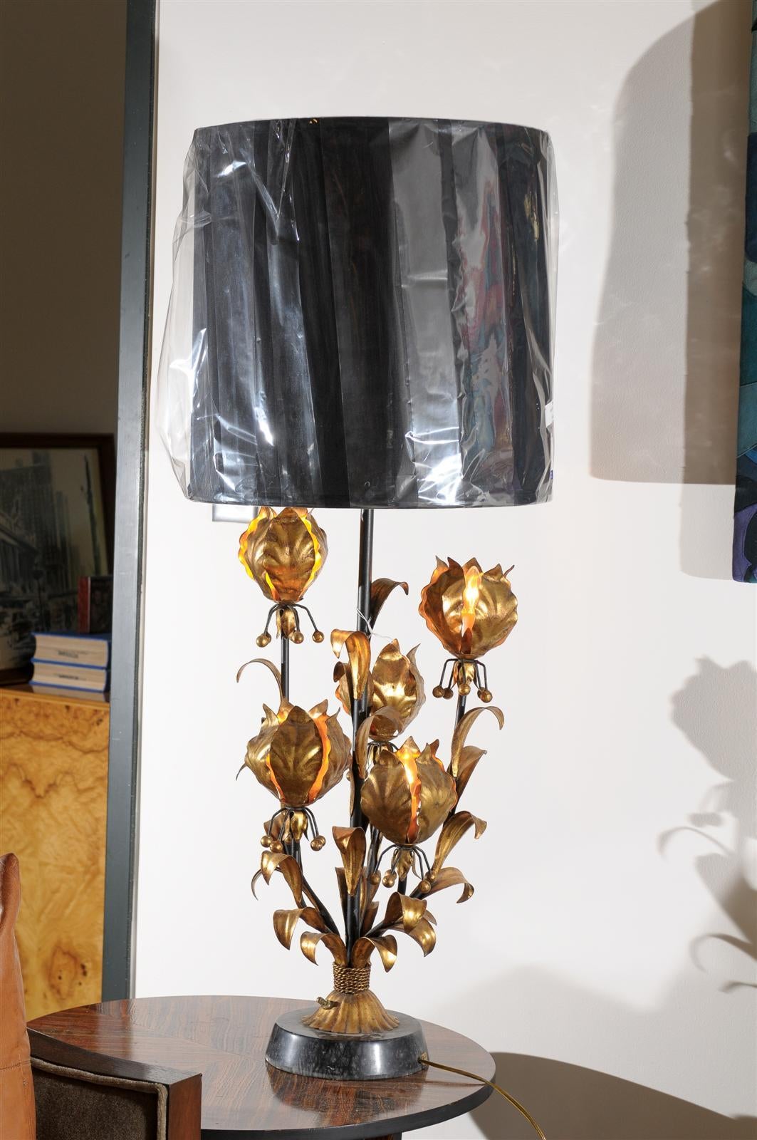 Midcentury Italian tall table lamp with a stone base and an upright surrounded by gilt metal in the shape of lotus blossoms. Each of five is illuminated by a candelabra bulb controlled at the base. An additional light crowns the lamp and is