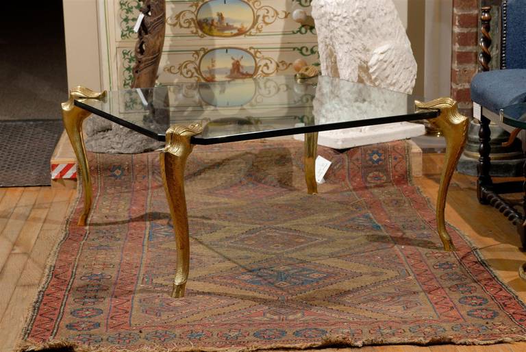 20th Century square cocktail table with thick glass top supported by four cabriole cast bronze legs with hoof feet.