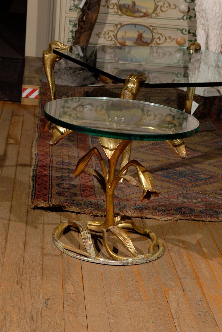 This Hollywood Regency side table is of gilded aluminum and in the form of a lily.  It supports a thick circular glass top and was designed by Arthur Court in the 1960's.