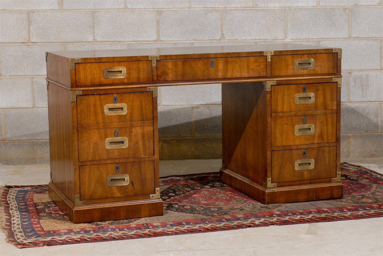 Mid 20th Century pedestal partners desk in the campaign style with brass hardware.  The desk is made by Henredon and has seven drawers including two file drawers.