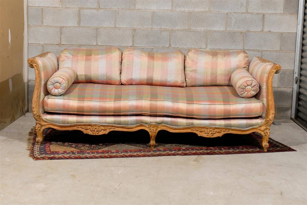 Hollywood Regency sofa or canapé with a pickled and carved wood frame with Louis XV style details. The sofa is upholstered in a striped silk with feather down cushions.
