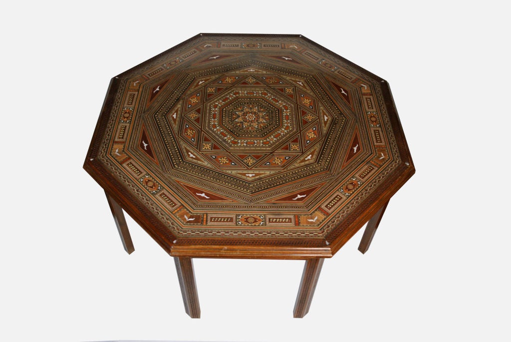 Octagonal-Shaped Moorish Style Cocktail Table. It is inlayed heavily with Mother-of-Pearl and several exotic rare and colorful natural woods in the Mosaic design. Edges and legs are heavily carved and ornate in the arabesque design. Glass top.