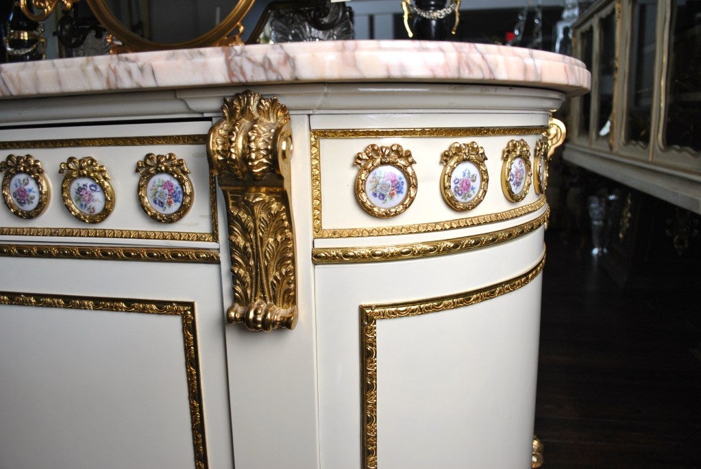 Spanish Dining Service Cabinet by Mariner. Decorated with a frieze of floral porcelain medallions within gilt wreaths. Gilt-decorated wood against a crème peint ground. Sits on gilt-metal paw feet. Mottled marble top in brown and ecru. Branded with