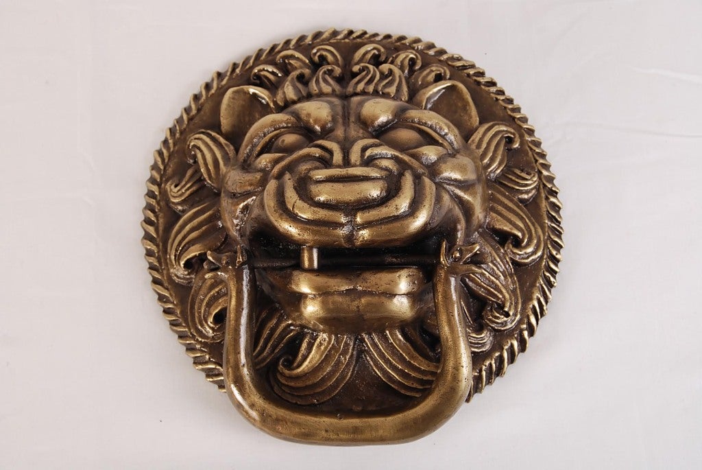Foo Dog Bronze Door Knocker. This large and heavy bronze door knocker has the detailed facial features of a foo dog and supports a hanging knocker in the form of a two-headed figural creature.