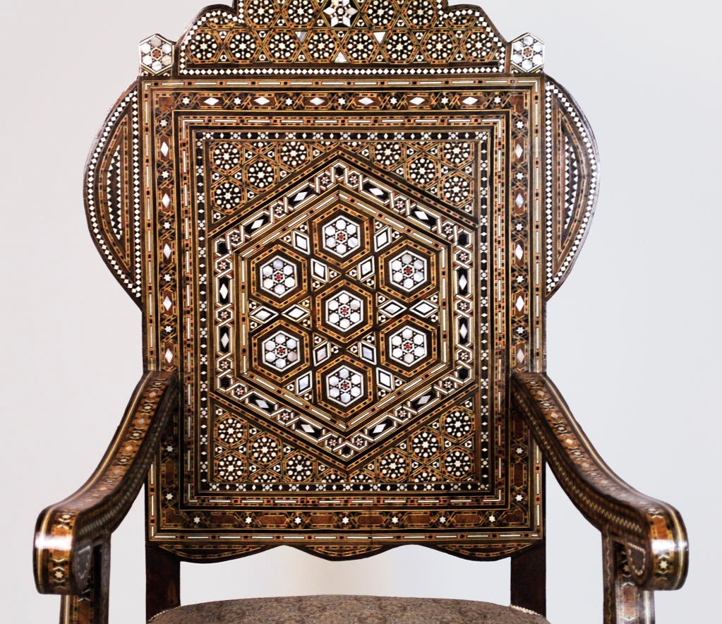 Moorish Style Mother of Pearl Inlaid Armchair. This chair is mother of pearl wooden mosaic inlay with a shaped cornice and apron. The seat of the chair is in a crème colored fabric with blue and gold embellishments. 4 chairs available