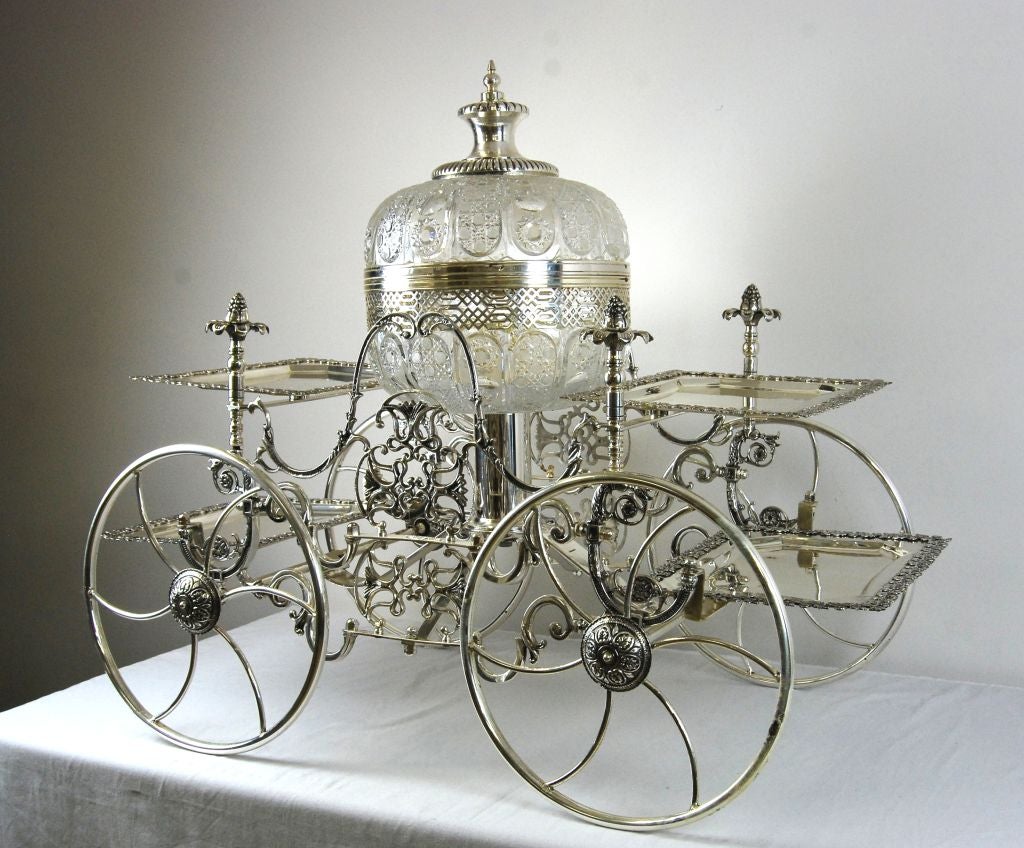 Crystal and Silverplated Portable Bar Trolley. Portable bar in the form of a carriage and mounted on four wheels. Partially pierced silverplated frame and crystal dome. Interior receptacles for four wine or spirits bottles. Four serving salvers