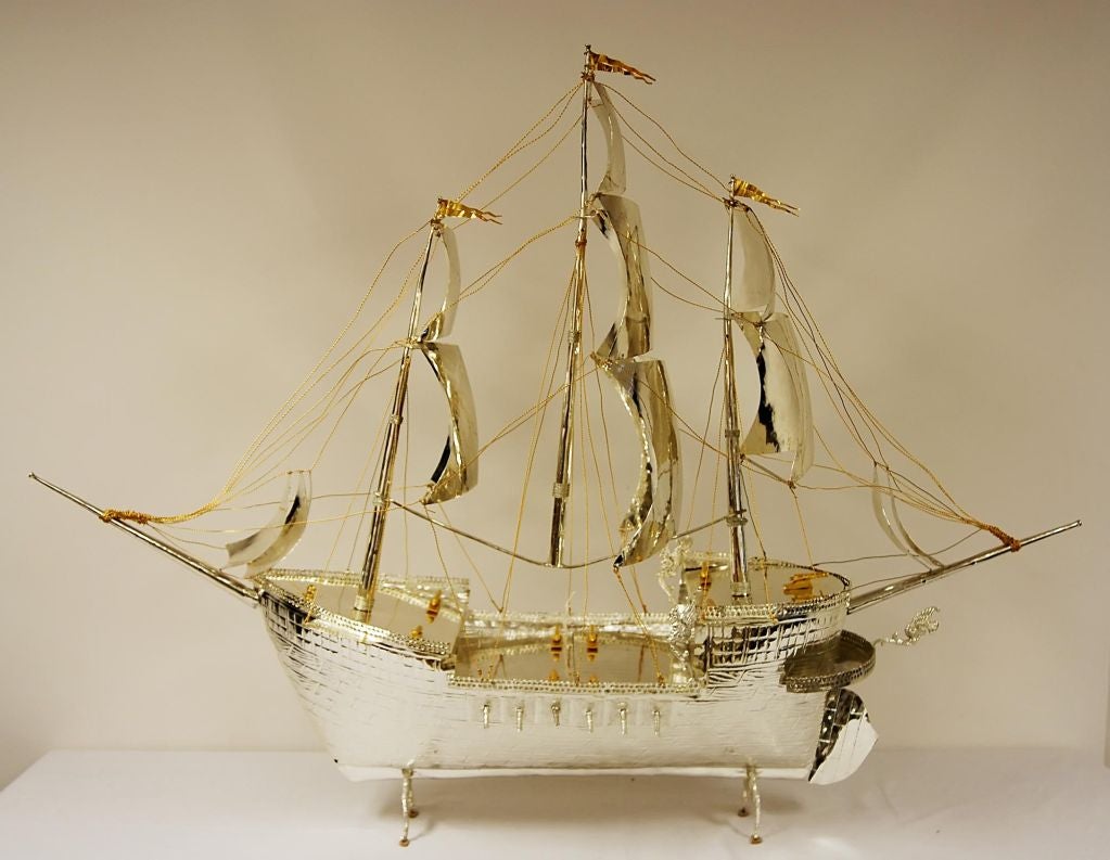 Silverplated Replica of 18th Century Spanish Galleon. Table model of a Spanish Armada warship. Three masts, twelve sails, three flags, and rigging. Nine gilt cannons on the deck and six battle guns projecting at each side of the hull. Gargoyle motif