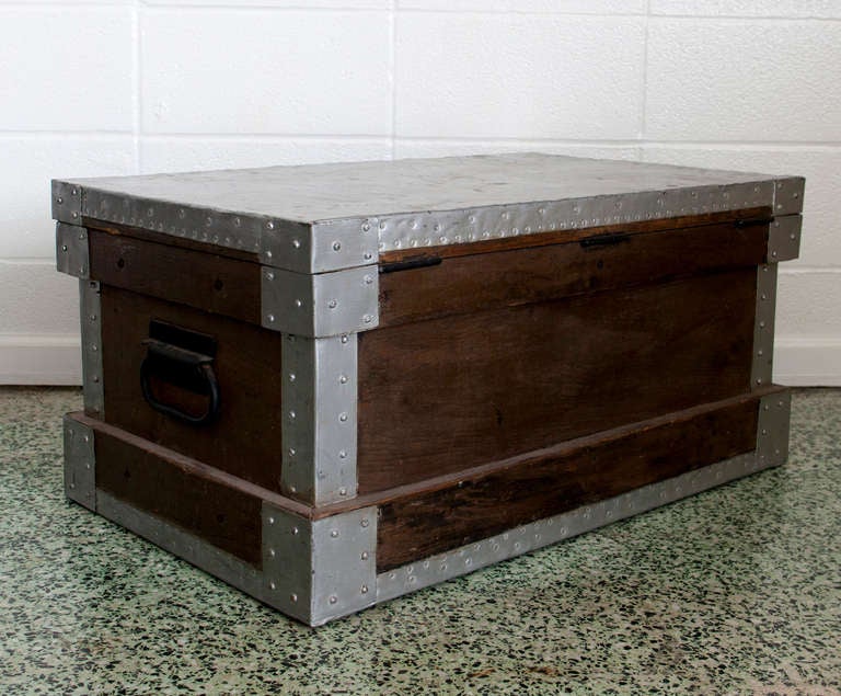 Bare metal trunk with exposed rivets and dark hardware. Great industrial style. Perfect storage and function, used as a bench or coffee table.