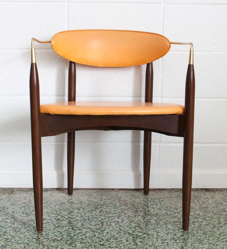 Early mid-century modern chair design by American architect Dan Johnson. They were produced and distributed by Selig in the US. This design is light, lean, and elegant. A slender brass rod wraps around the seat back and attaches to the tops of the