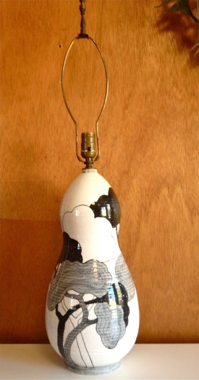 A unique tall ceramic table lamp, hand thrown and hand painted with majestic trees  in black and gray on a white glazed ground. Signed to the base. By Ernestine. Italian.