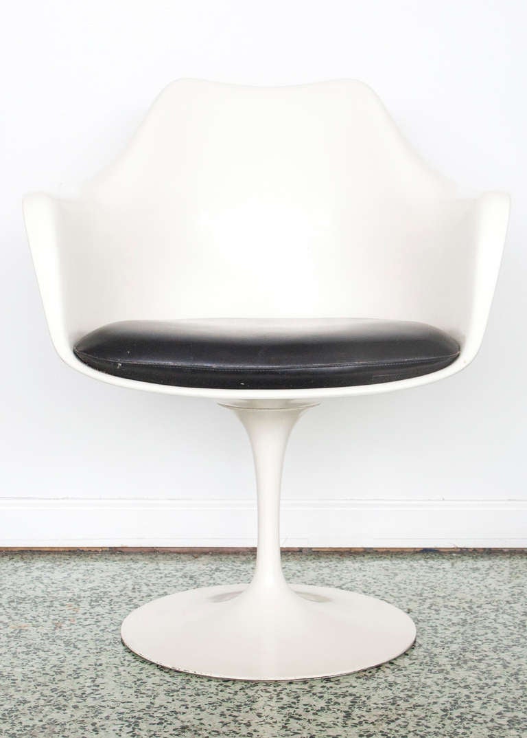 4 dining chairs with arm shell and upholstered seat on a white enameled cast iron pedestal base. Black seat cushions manufactured by Knoll Associates.