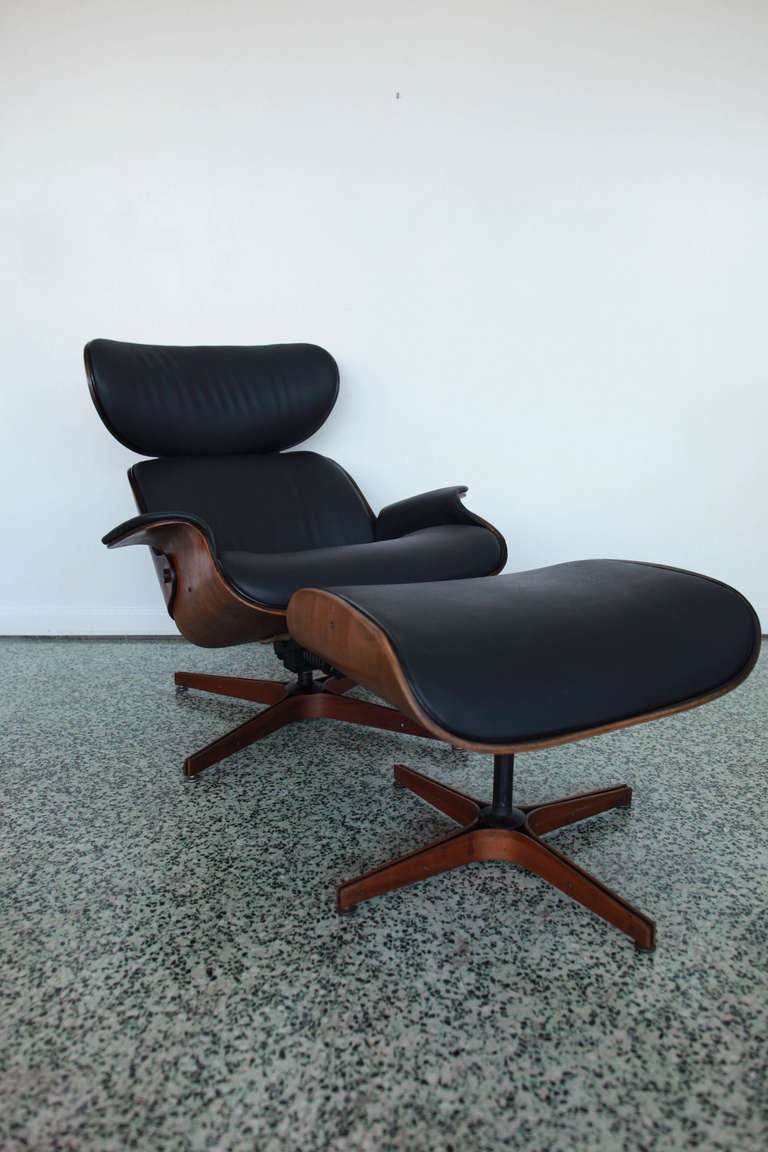 A mid-century modern black swiveling lounge chair and ottoman for Plycraft. Molded walnut shells and bases. Newly reupholstered.