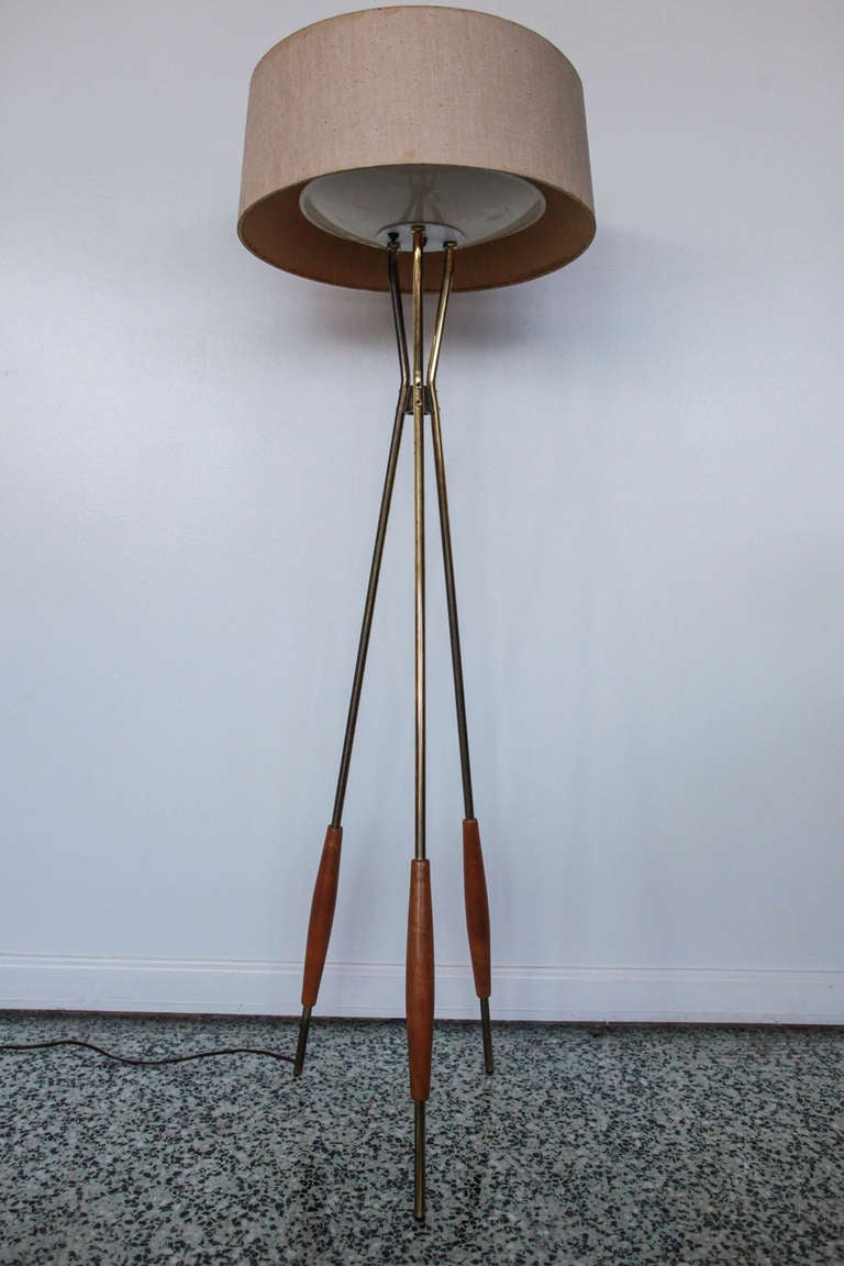 All original Gerald Thurston For Lightolier Tripod Floor lamp. Brass legs with walnut sleeve support linen shade that has metal and plastic bulb diffusors. We have a matching pair of table lamps also available.