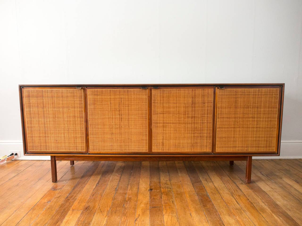 Very nice walnut credenza with lather tab pulls and cane front doors. Doors conceal a pair of shelves and a pair of drawers. 

A second walnut case sits atop the credenza, or could be fitted to float on the wall. Excellent vintage condition. Wear