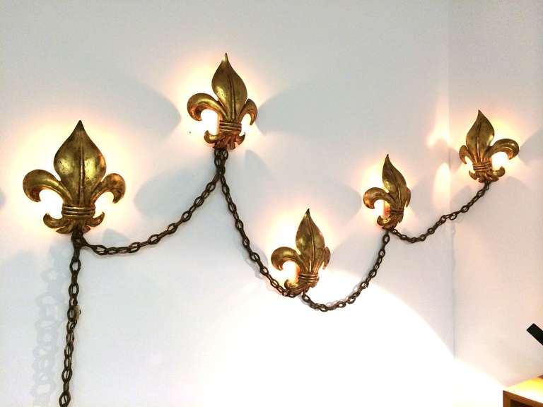 Hollywood Regency gold gilt Fleur De Lis design wall light on swag chain.