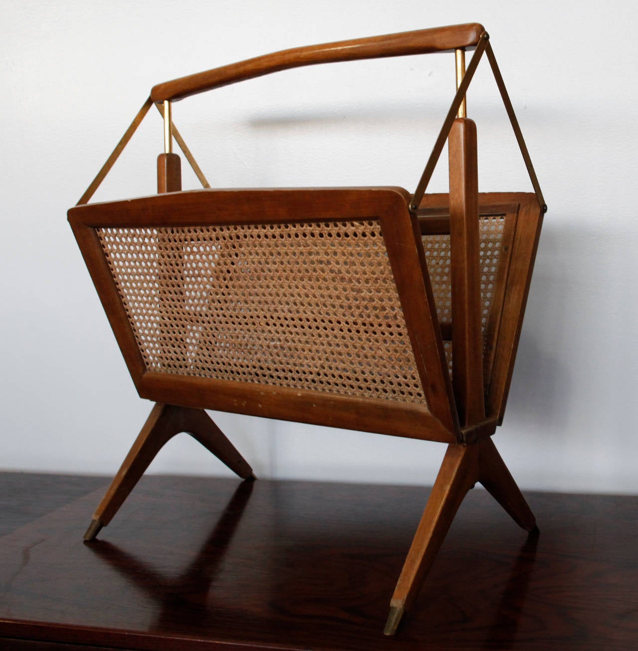 Mid-Century sculptural walnut, caning and brass magazine rack manufactured in Italy, circa 1950s. In the manner of Gio Ponti. Magazine rack closes when you hold handle. Original finish.