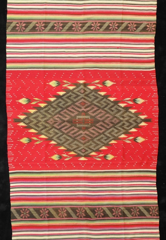 Large central complex diamond with manita flowers radiating horizontally from diamond. This serape is of unknown origin but possibly from south central Mexico, possibly Puebla. The overall effect of the design is one of restrained elegance.