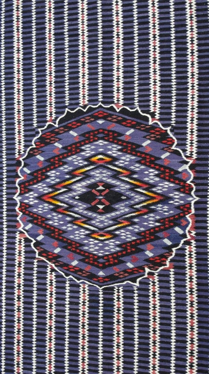 Beautiful hand woven Saltillo serape with large complex central diamond enclosed by scalloped medallion. The field is filled with multiple zig zag lines and alternating black and purple horizontal stripes. The edges composed of polychrome diagonal