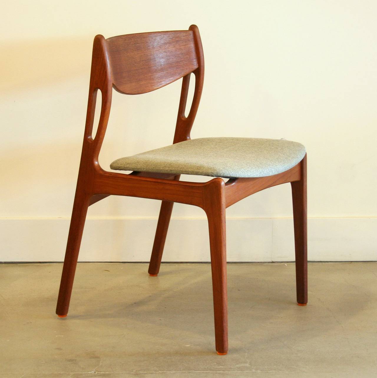 Crafted from solid teak wood, features a unique detail on the sides of its back. Freshly reupholstered. Sold as a set of six.