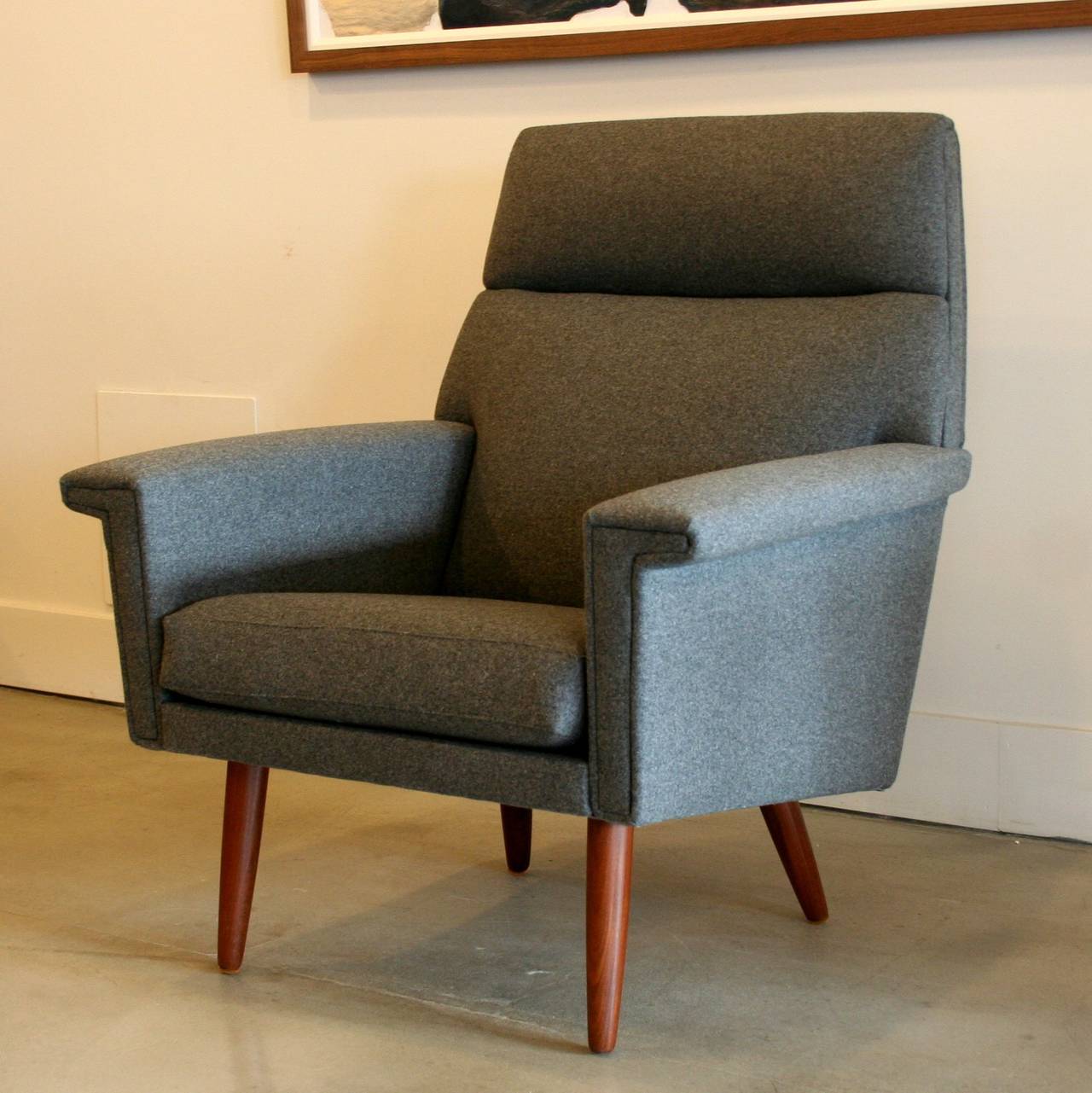 Timeless mid-century design, this stunning armchair has been newly reupholstered in grey felted wool. High tight back frame with finned arms and loose cushion seat. Resting on solid teak conical legs