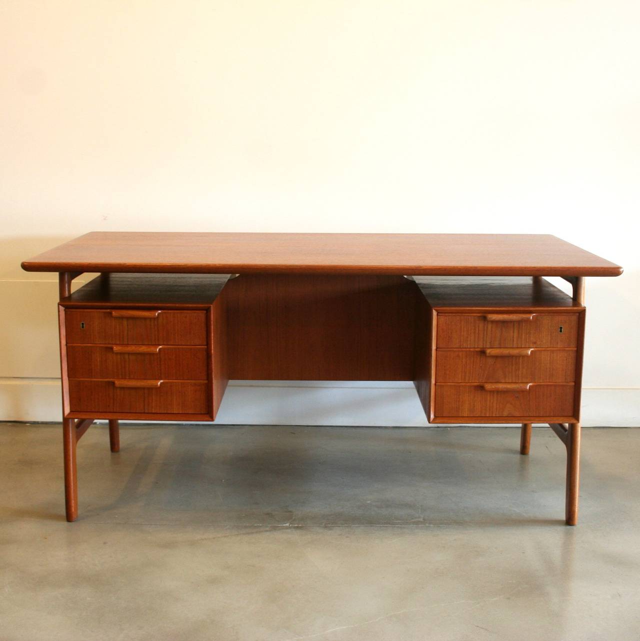 Stunning original teak desk designed by Gunni Omann, circa 1950's. This piece is highly functional and beautiful to look at. Rounded edges and sculptural A-frame leg design create an organic aesthetic, while six dove-tailed drawers and rear drop