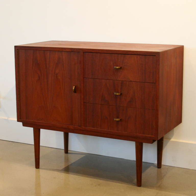 Unique little chest crafted in teak with half-moon pulls on the drawers and cabinet door. Conical teak legs, rich patina, and a small scale which makes it great beside the bed or sofa. Made in Denmark.