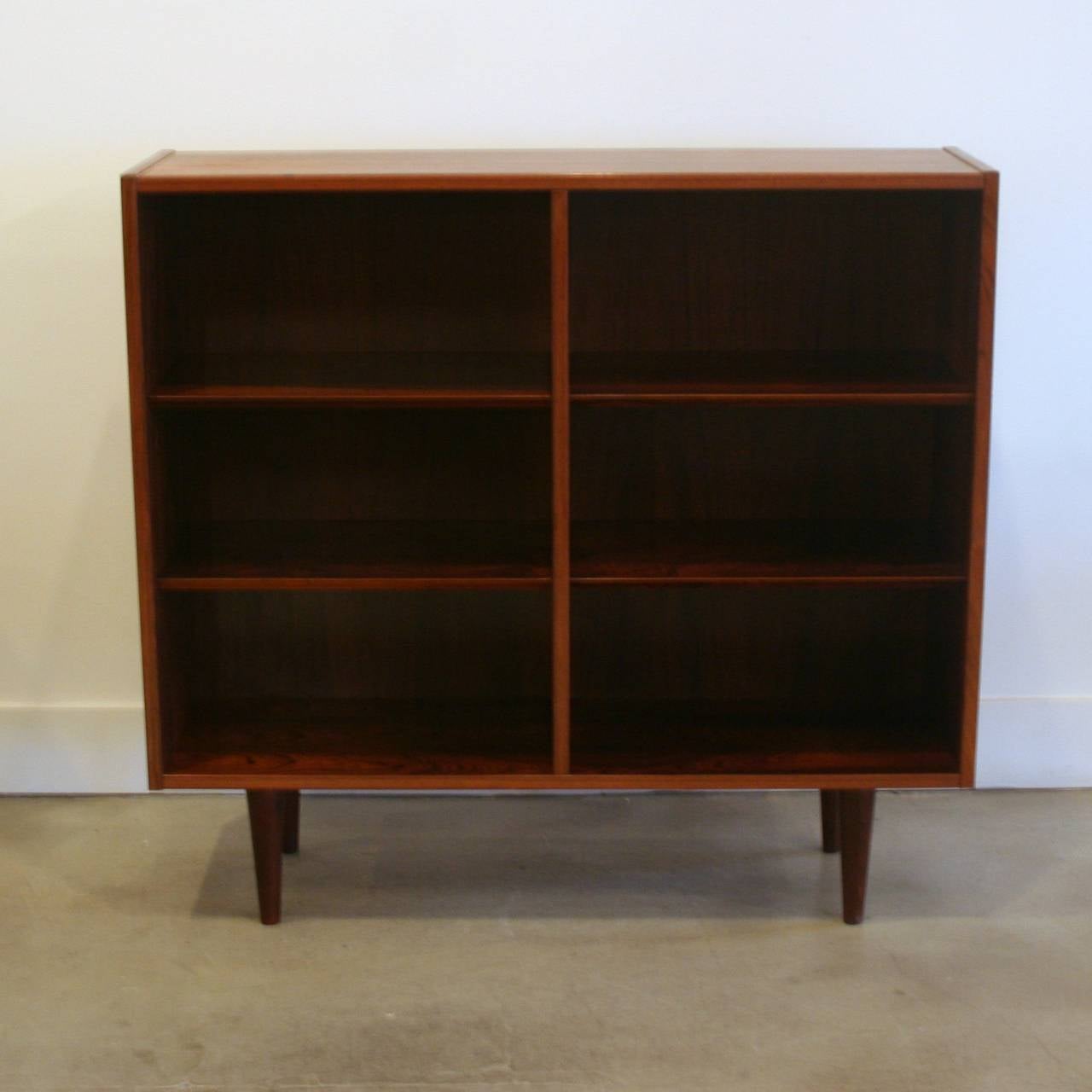 Stunning low rosewood bookcase with four adjustable beveled edged shelves. Resting on solid conical legs.