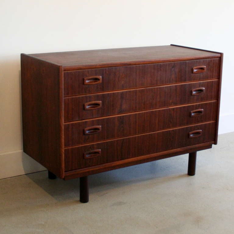 A lovely chest of drawers crafted in Brazilian rosewood, made up of four drawers with inset pulls, and round legs. This storage piece works well alone or beside a bed doubling as a nightstand. Made in Denmark.
