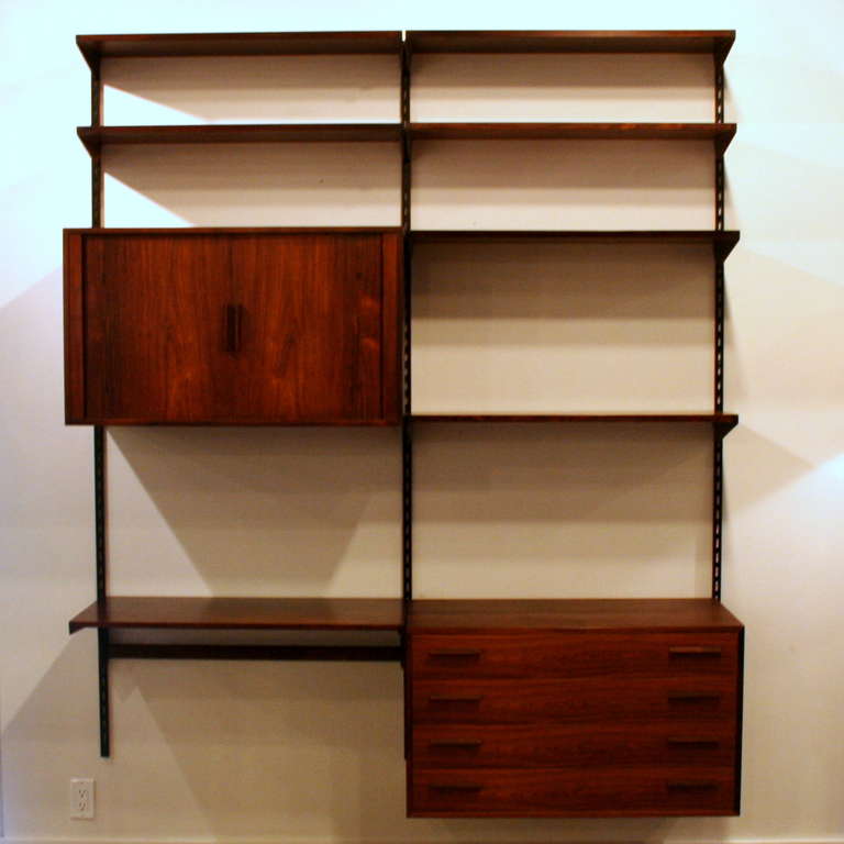 A beautiful, well-crafted vintage rosewood wall system designed by Danish designer Kai Kristiansen.  Black metal rails support a variety of storage pieces, including a drawer unit with 4 dove-tailed drawers and a cabinet with tambour doors that