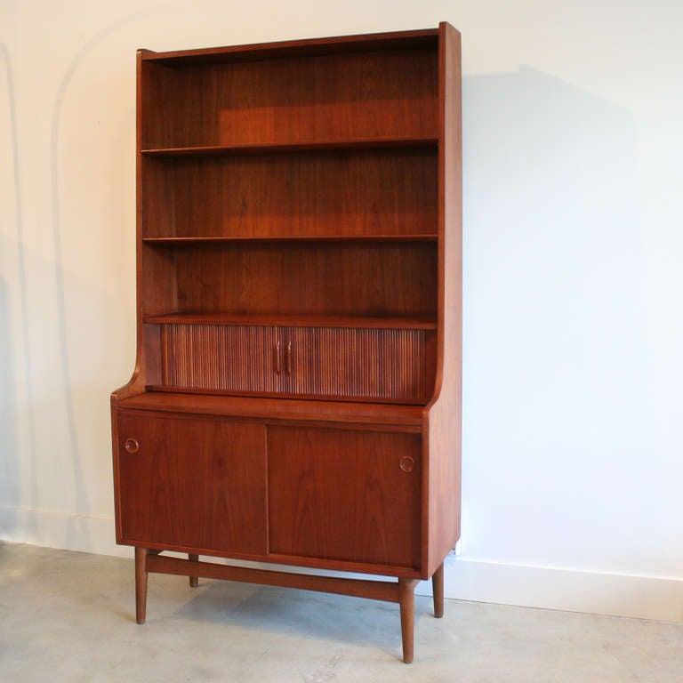 A stunning and distinctly Danish modern piece with multiple storage options, including adjustable upper shelves and lower cabinet. The pull-out desk surface is great for a laptop and the sliding tambour doors in the center open to reveal a smaller