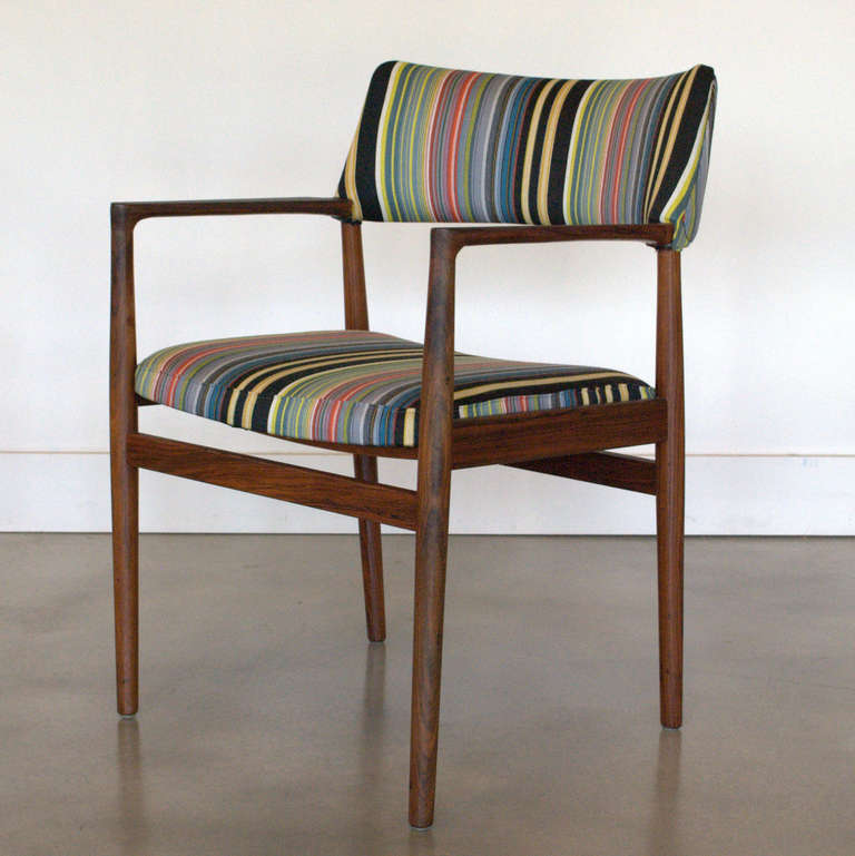 Newly reupholstered in a fun, colourful stripe fabric, by Paul Smith; this solid rosewood chair is perfect to accent a space. Sleek arms and rounded edges add a sense of minimalism to the piece.