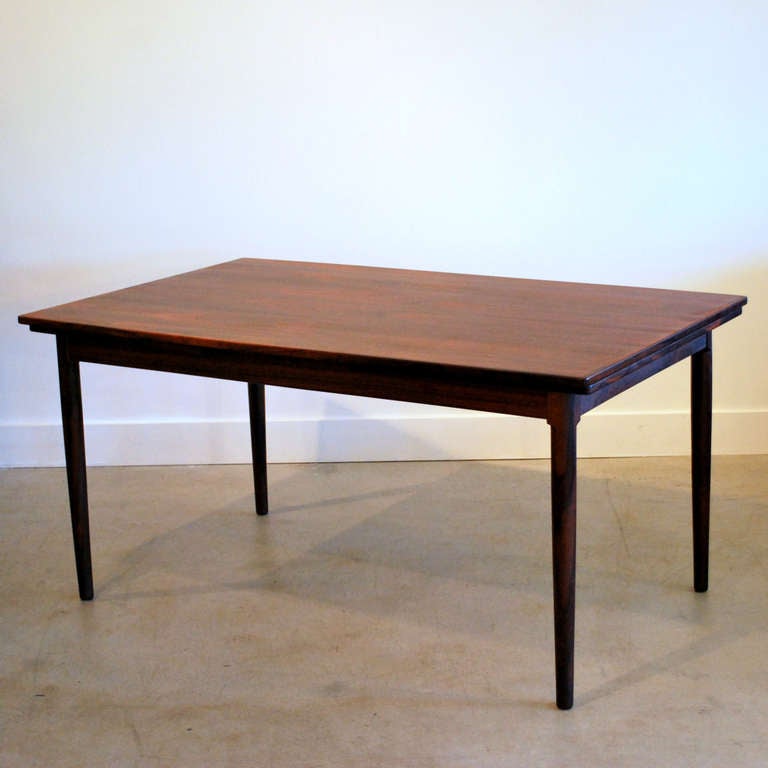 The exquisite patina of the rich Brazilian rosewood is masterly crafted into this beautiful table by J.L. Mollers. Shaped with a slight bow on the long side, the table extends out to comfortably seat up to eight people. Resting on solid rounded