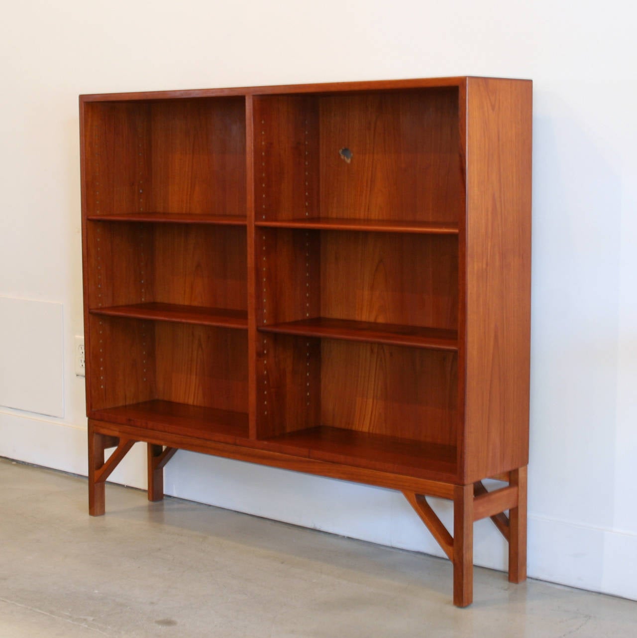 Low and wide vintage teak bookcase by Borge Mogensen. Adjustable shelves with beveled edge. Resting on solid teak legs. Two available, sold individually. Made in Denmark.