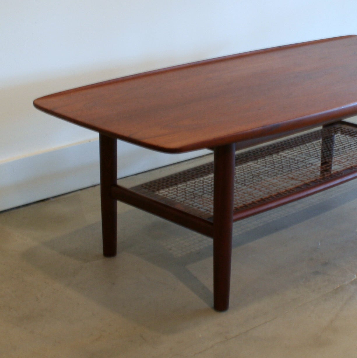 Beautiful vintage Danish coffee table with exquisite grains and colours. Subtle surfboard shape and lip sides to the top with a sturdy feel that contrasts nicely with the cane detail.