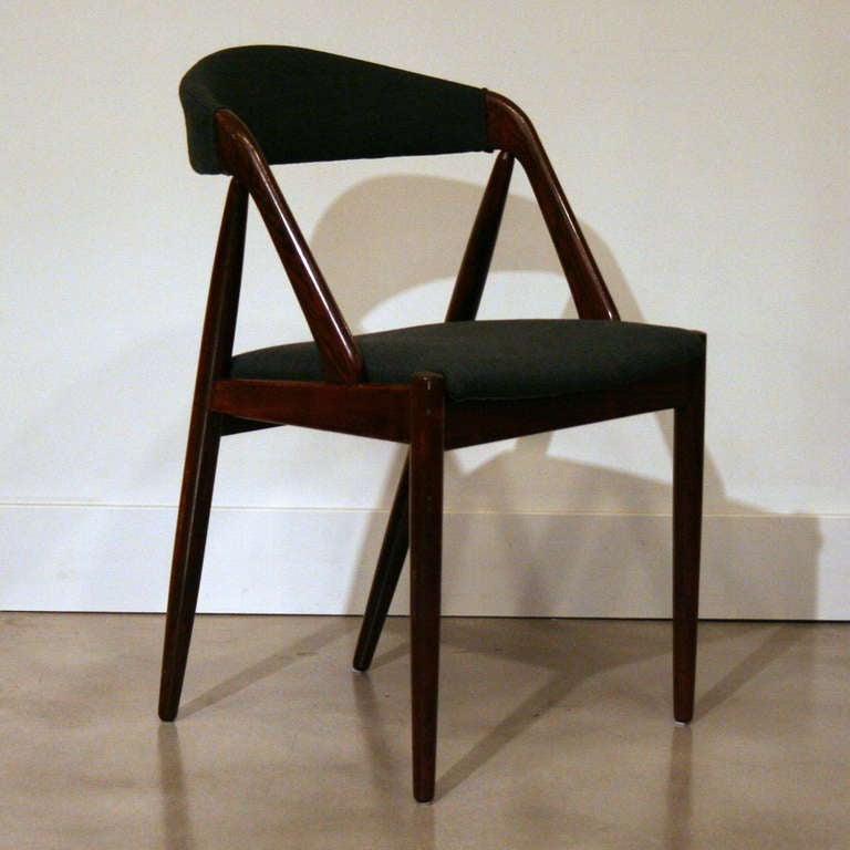 A set of six unique dining chairs by well-known Danish designer, Kai Kristiansen, beautifully crafted in solid rosewood. Featuring the designer's signature angled rear legs and a backrest that gently cradles your back with support. Backs and seats