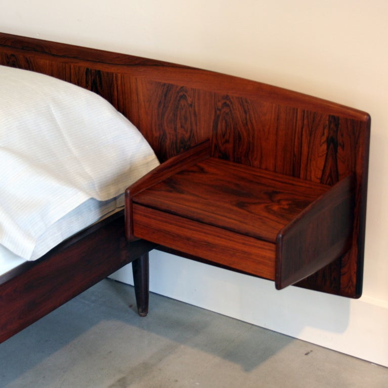 Stunning rosewood grains adorn this handsomely crafted bed, complete with floating side drawers, conical wood legs, and low profile design. Recently modified from European size to accommodate a North American queen size mattress.  Dove-tailed