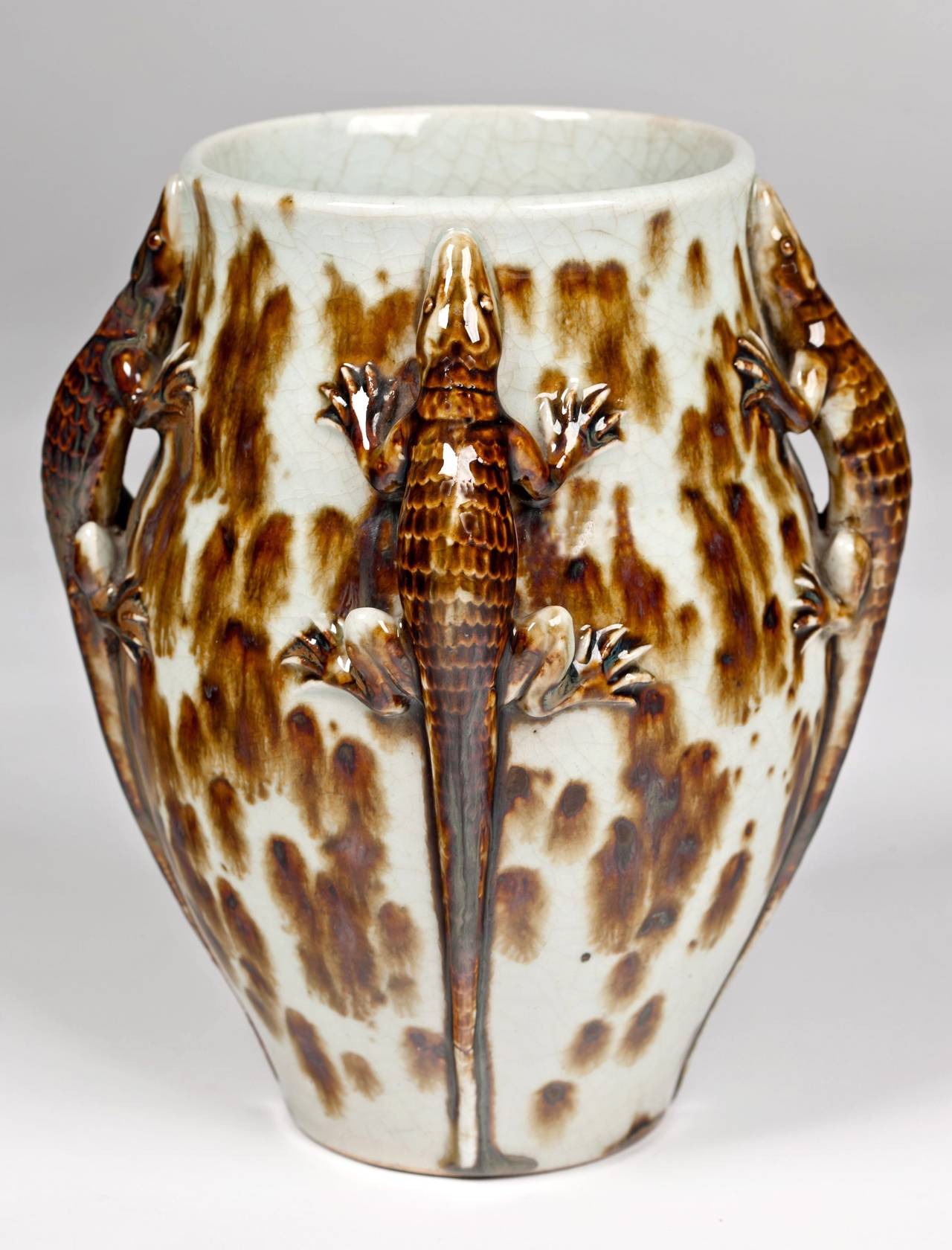 An outstanding French deco Primavera vase with lizards surrounding the sides in a mottled brown and white glossy craquelure glaze. Signed Primavera.

Note: Camera flashes on vase.