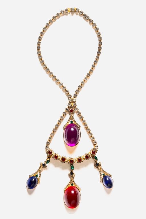 Exceptional and Rare signed HATTIE CARNEGIE necklace featuring individually prong set clear, red and green crystal rhinestones set in gilt metal accentuated by large red, purple and blue poured glass cabochons.

Large central cabochons measure 2 x